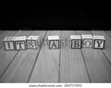 Black and white image of toy blocks on a wooden floor spelling out \