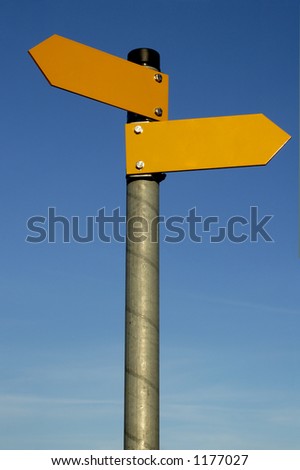 Two arrows on a pole pointing in different directions, against a clear blue sky.