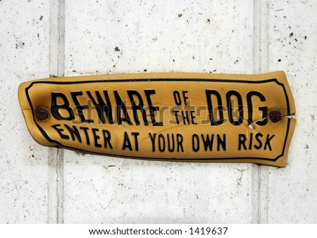 A grungy, distorted, \'Beware of the Dog\' sign, nailed to a wooden gate. Clipping path, around the sign, included so it can be extracted and placed on any other background.