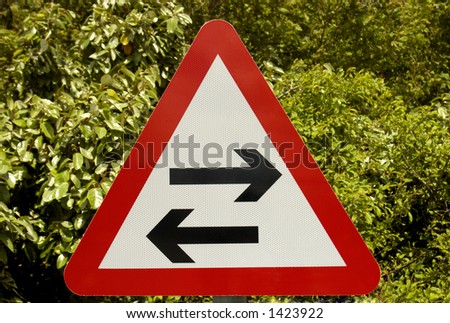 A two-way sign, arrows pointing in opposite directions, on a green leafy background. Clipping path included so sign can be isolated.