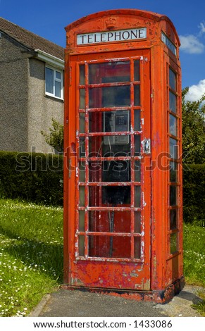 A grungy British telephone box on a council estate in a Welsh village. Council house in the background.