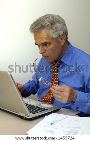 A businessman looks at his laptop computer as though it\'s about to explode. Something has gone seriously wrong.