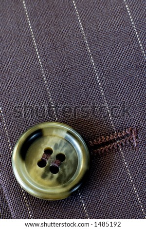 Macro of a buttonhole in a businessman\'s pin-stripe suit. Texture and light.