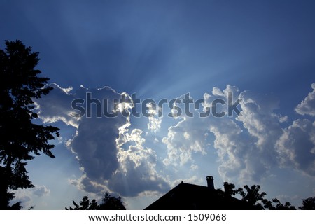 Rays of sunlight burst out from behind a toweing cumulo-nimbus thunderhead, into a rich blue sky. Space for text on in sky.