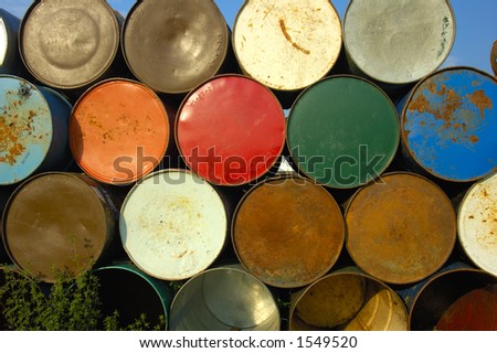 A stack of grungy old oil drums at a music festival, ready to be set out as rubbish bins.