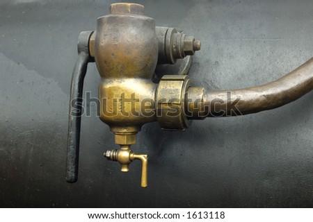 Detail of a brass valve, of unknown purpose, on the side of the boiler of an old steam engine.