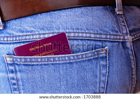 An EU/UK passport pokes out of the rear pocket of someone\'s jeans. A temptation for a pickpocket.