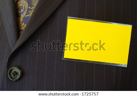 Close-up of a blank yellow name-tag on a businessman\'s pin-striped suit. Space for text on the tag.