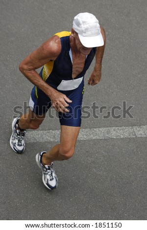 An older runner in a triathlon race, taken from above. Motion blur on his feet.