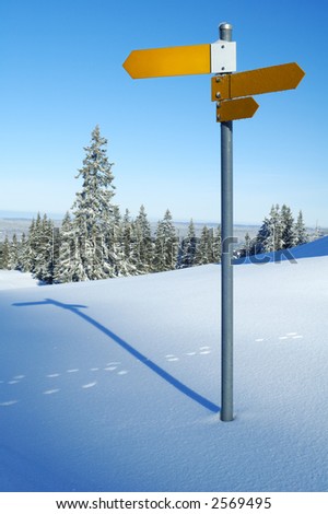 An isolated signpost, in snowy mountains, space for text on the sign, or in the sky.