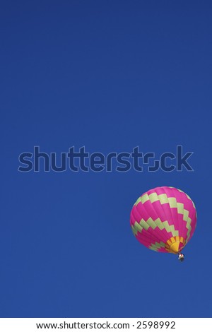 A solitary hot-air balloon flying high in a clear blue sky.