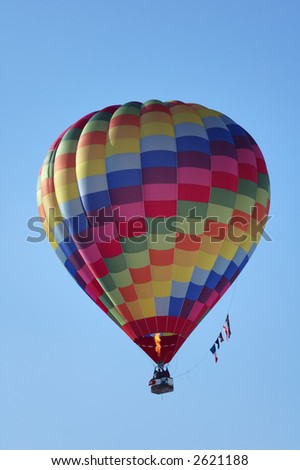 A hot-air balloon flying the flags of UK, USA, EU and France. The pilot is operating the burner.