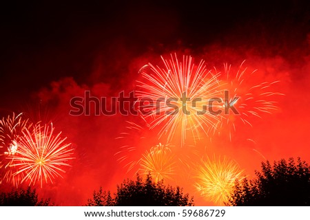 Fireworks exploding in the night sky against a background of red smoke. Space for text in the dark of the night sky.