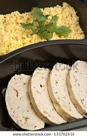 Slices of white meat roulade with curry rice in a plastic take out container