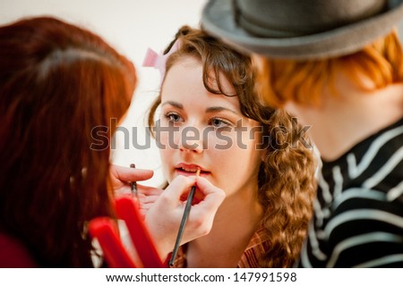 Beautiful young woman having her make up done by a make up artist in a studio