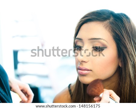 Attractive young asian indian woman having her make up done by a make up artist