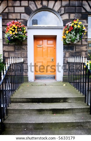 An historic European entrance way with bright orange door
