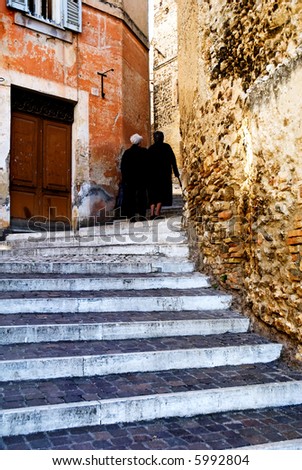 Two old Italian ladies walking up ancient steps in an Italian village