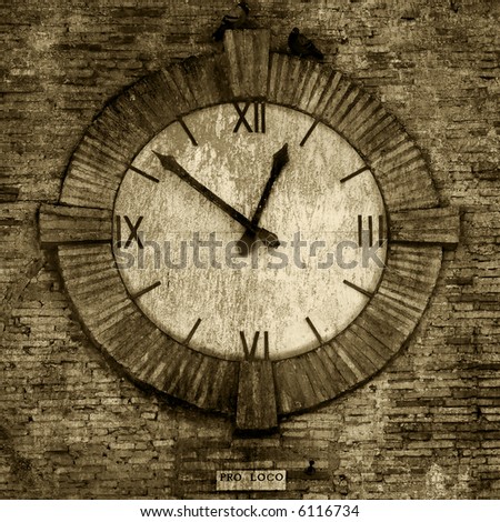 Old-fashioned clock on the side of an old brick wall, from a medieval village in europe with sepia texture.