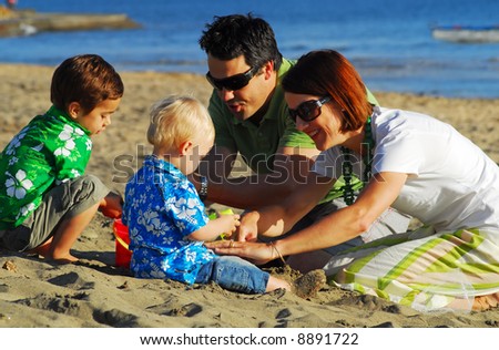 Young family playing at the beach in the morning sun...