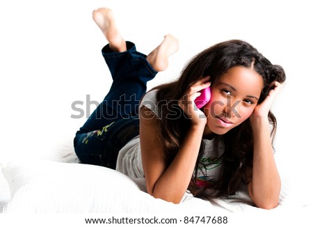 Concerned teenage girl on a pink cell phone lying down listening with legs crossed feet in the air - isolated on white