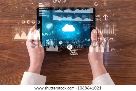 Hand holding tablet and checking finantial report on cloud computing system
