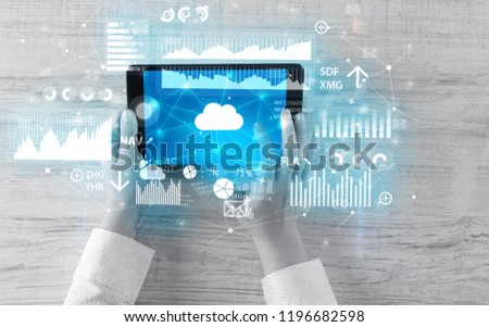 Hand holding tablet and checking finantial report on cloud computing system