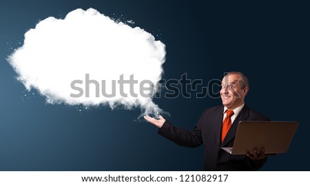 Businessman in suit holding a laptop and presenting abstract cloud copy space