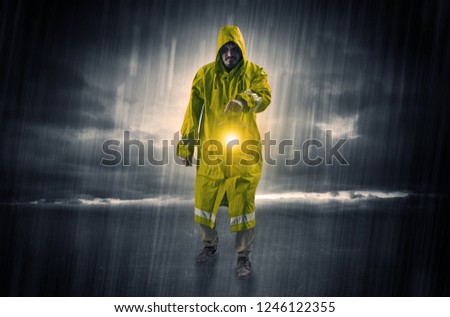 Raincoated man walking in storm with glowing lantern in his hand