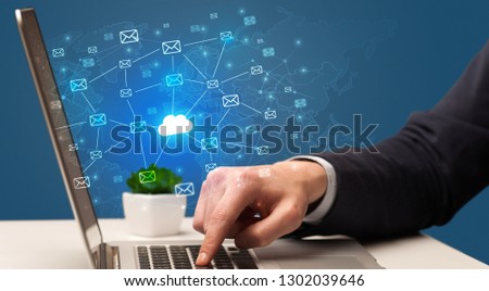 Businessman hand sending a bunch of messages on laptop with cloud computing concept