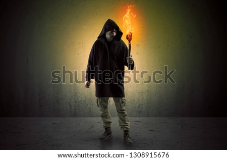 Ugly scary man with burning flambeau walking in an empty space