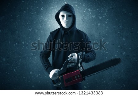 Masked armed villain in empty dark room with gun ax chainsaw mallet wrench