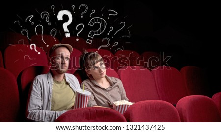 Nice couple in cinema with drawn question signs around