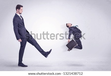 Big man in suit kicking out little himself out with simple white wallpaper