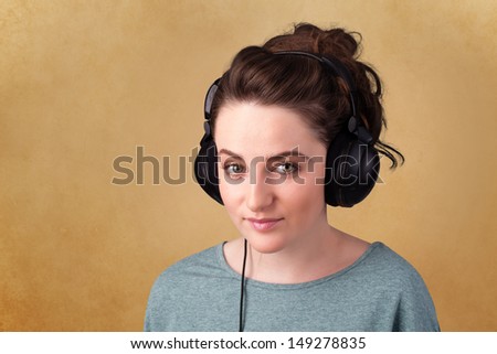 Pretty young woman with headphones listening to music with empty space