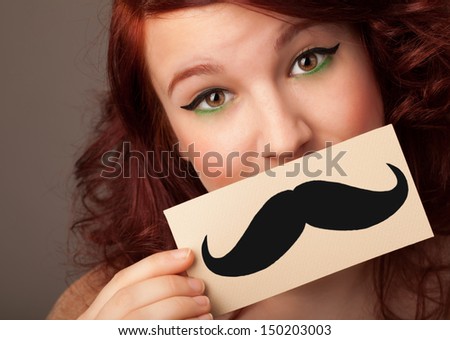 Happy cute girl holding paper with mustache drawing on gradient background