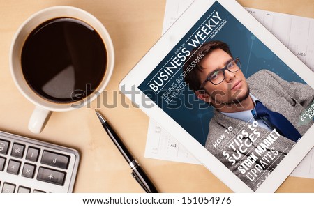 Workplace With Tablet Pc Showing Magazine Cover And A Cup Of Coffee On A Wooden Work Table Close-Up