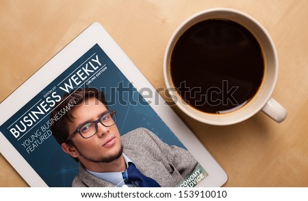 Workplace With Tablet Pc Showing Magazine Cover And A Cup Of Coffee On A Wooden Work Table Close-Up