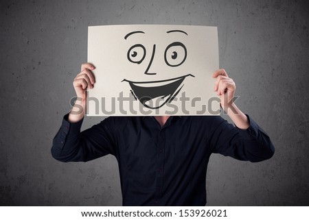 Young businessman holding a cardboard with a smiley face on it in front of his head