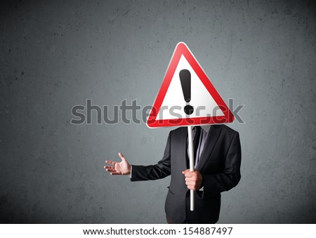 Businessman holding a red traffic triangle warning sign in front of his head