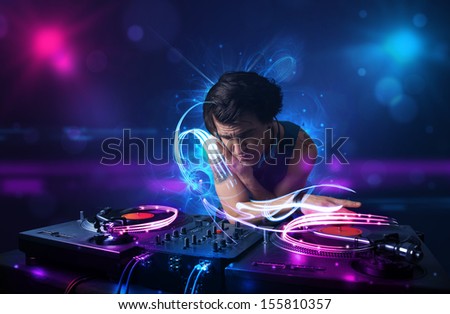 Young disc jockey playing music with electro light effects and lights