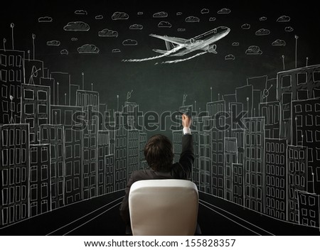 Young businessman sitting in an office chair and looking on a sketched cityscape drawing on a chalkboard