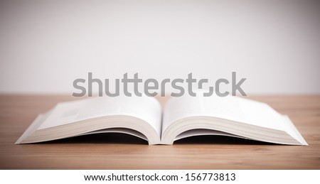 Open book with hand drawn landscape on wooden deck