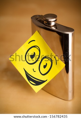 Drawn smiley face on a post-it note sticked on a hip flask