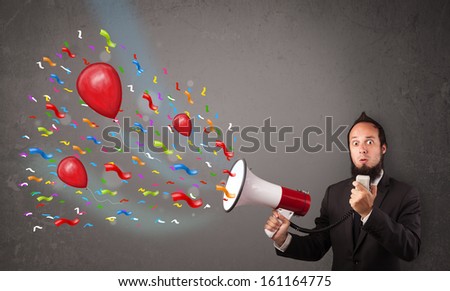 Young guy having fun, shouting into megaphone with balloons and confetti