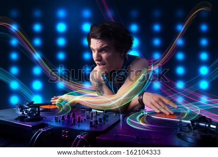 Attractive young Dj mixing records with colorful lights
