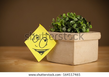 Drawn smiley face on a post-it note sticked on a flowerpot