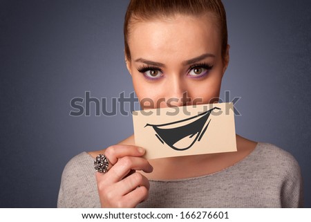 Happy cute girl holding paper with funny smiley drawing on gradient background