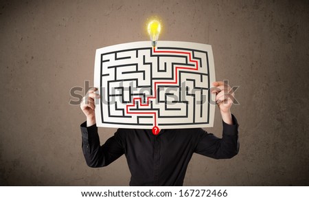 Young businessman holding a paper with a labyrinth on it in front of his head