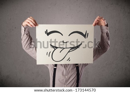 Young businessman holding a paper with funny smiley face on it in front of his head